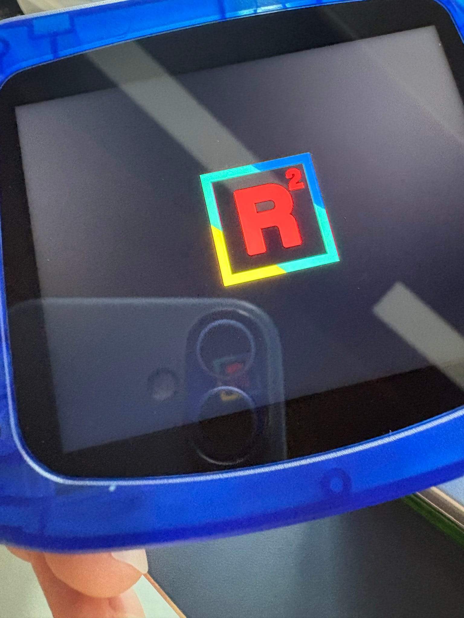 Close-up of the transparent-blue FPGBA SP shell showing the RetroRemake boot logo on screen.