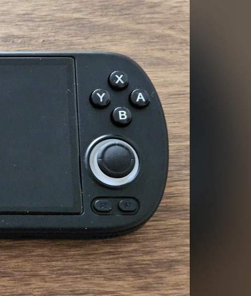 Close-up of a budget retro handheld's right controls, showing the analog stick and ABXY buttons