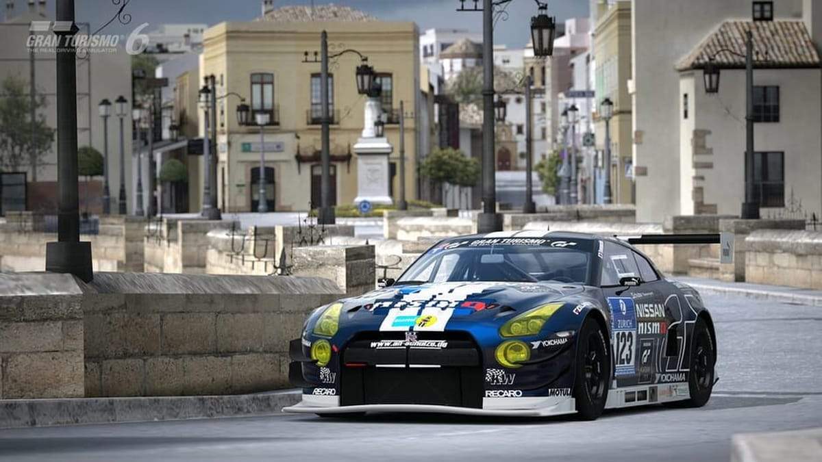Gran Turismo 6 gameplay screenshot showing a race car cornering through a city course